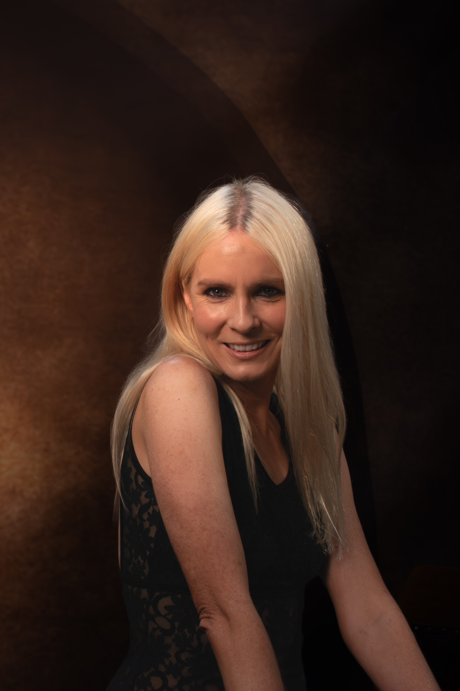 Close portrait of woman in black dress with warm studio lighting
