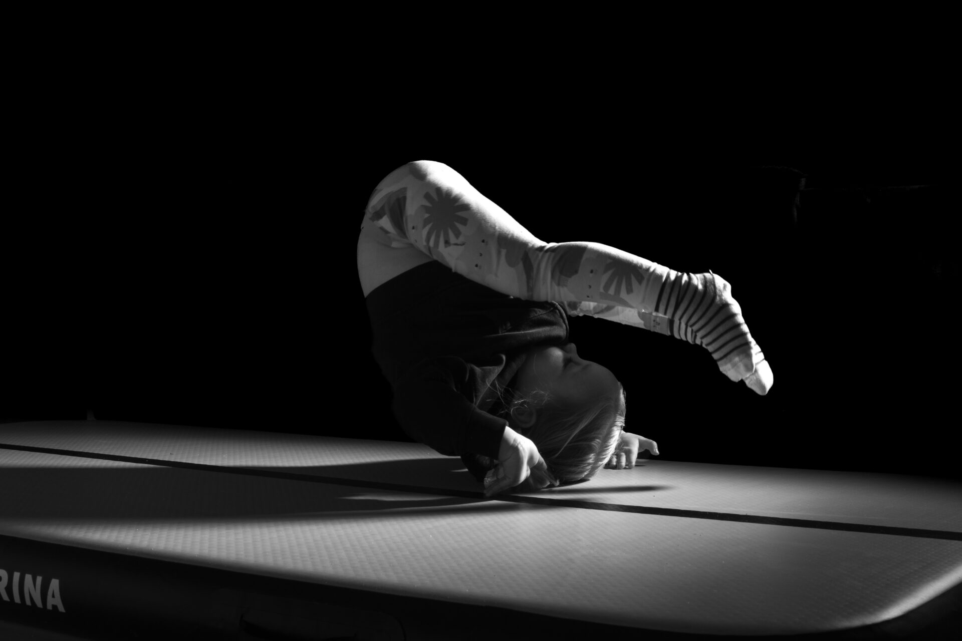 Baby upside down balancing on hands on a mat in black and white
