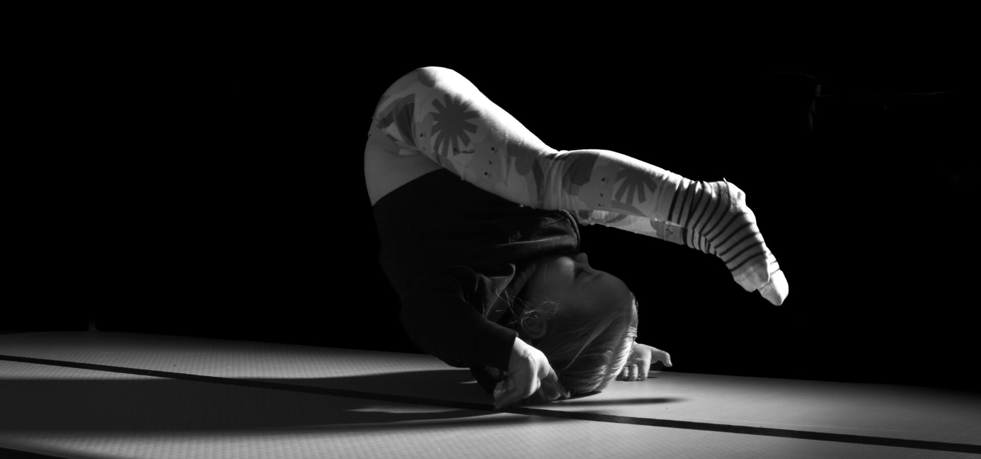 Baby upside down balancing on hands on a mat in black and white